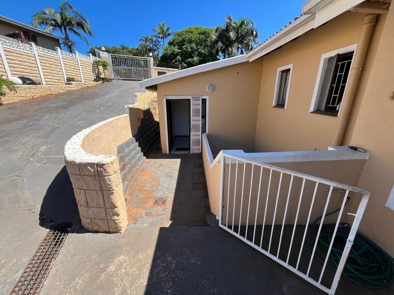 Rear exterior area featuring a paved walkway, retaining wall, and metal security gate access to the property.