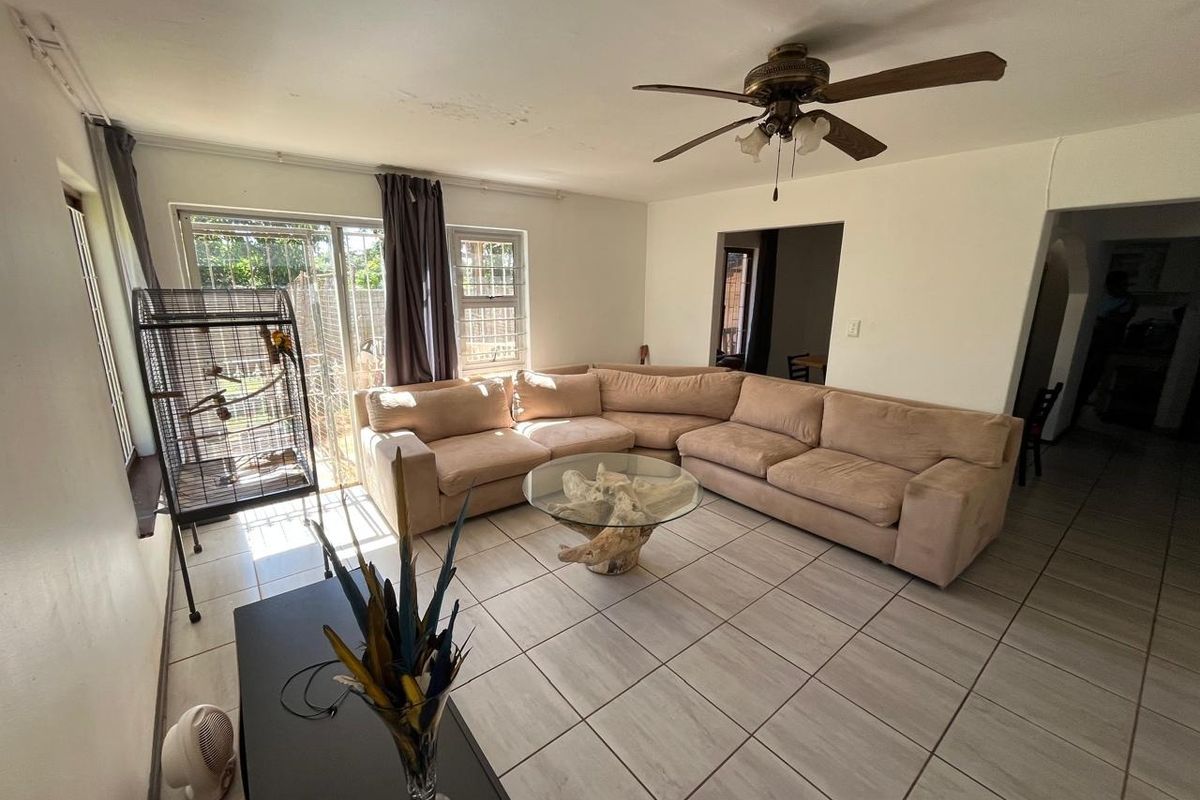 Spacious living room featuring tiled flooring, a ceiling fan, and sliding glass doors leading to the exterior.