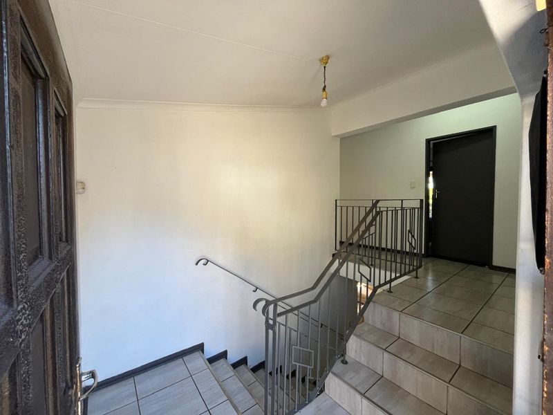 An entry area featuring a tiled staircase with a metal balustrade, leading to an upper level with neutral wall finishes.