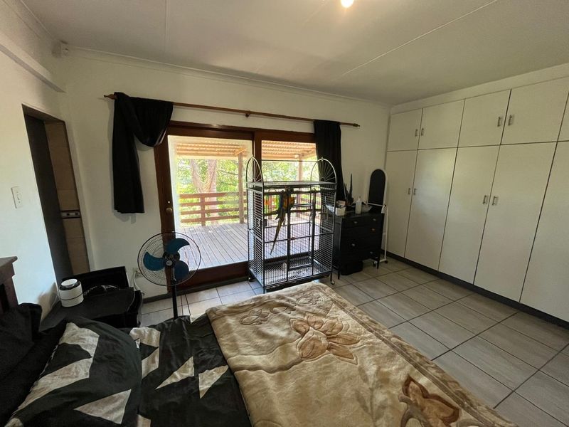 Spacious bedroom featuring built-in cupboards, tiled flooring, and a sliding glass door providing direct access to an outdoor deck area.