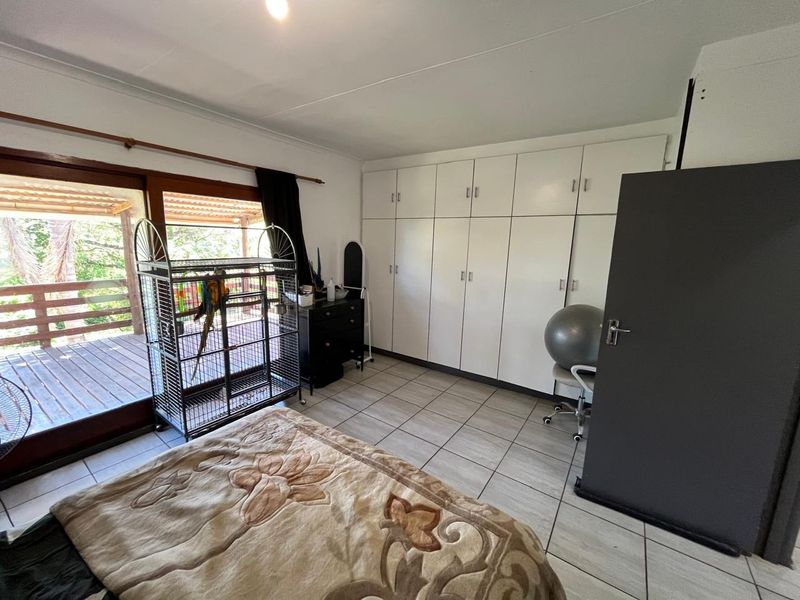 Bedroom featuring tiled flooring, extensive built-in cupboards, and a sliding glass door providing access to an outdoor deck area.