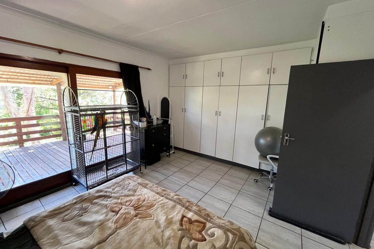 Bedroom featuring tiled flooring, extensive built-in cupboards, and a sliding glass door providing access to an outdoor deck area.