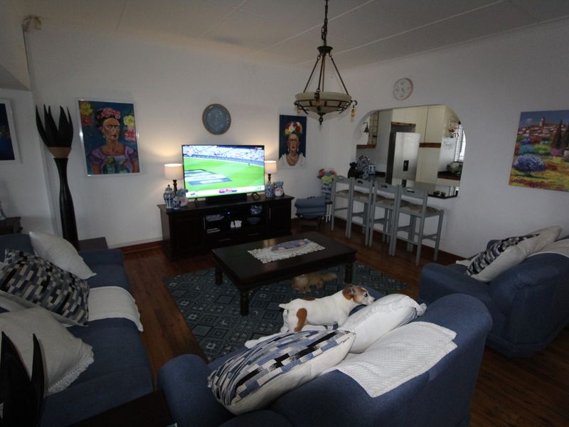 Open plan living area featuring hardwood flooring, a decorative pendant light, and a convenient pass-through window connecting to the kitchen space.