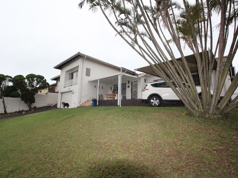 Front view of a residential house featuring a paved driveway, covered patio area, and an attached garage.