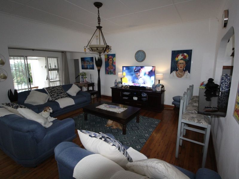 Spacious living room featuring hardwood flooring, a ceiling fan, and a breakfast bar, with direct access to an outdoor patio area.