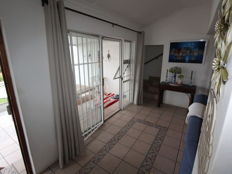 Living area featuring tiled flooring and sliding glass doors with security gates, providing access to an outdoor patio space.