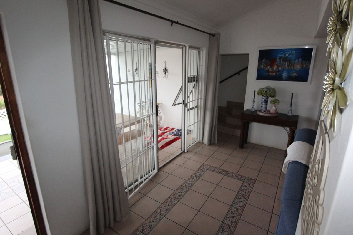 Living area featuring tiled flooring and sliding glass doors with security gates, providing access to an outdoor patio space.