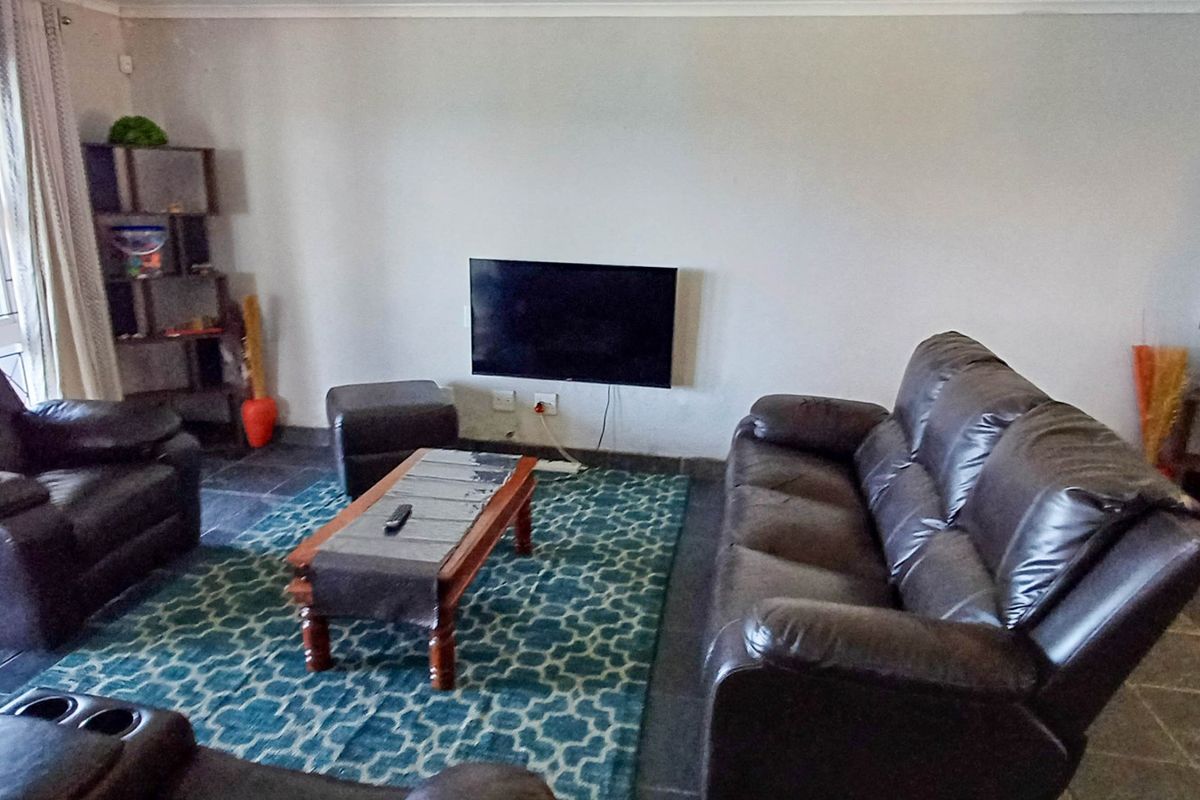 A living room featuring dark slate tile flooring and a wall-mounted television, providing a functional space with direct access to the exterior.