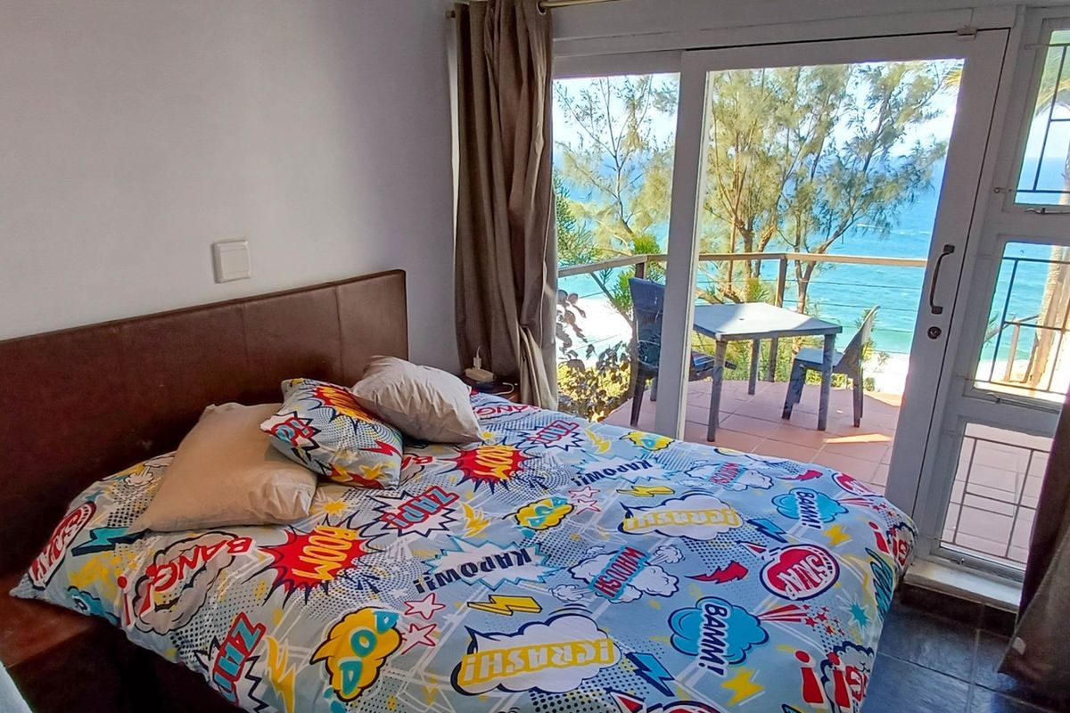 Bedroom featuring tiled flooring and a sliding glass door providing direct access to a balcony with ocean views.