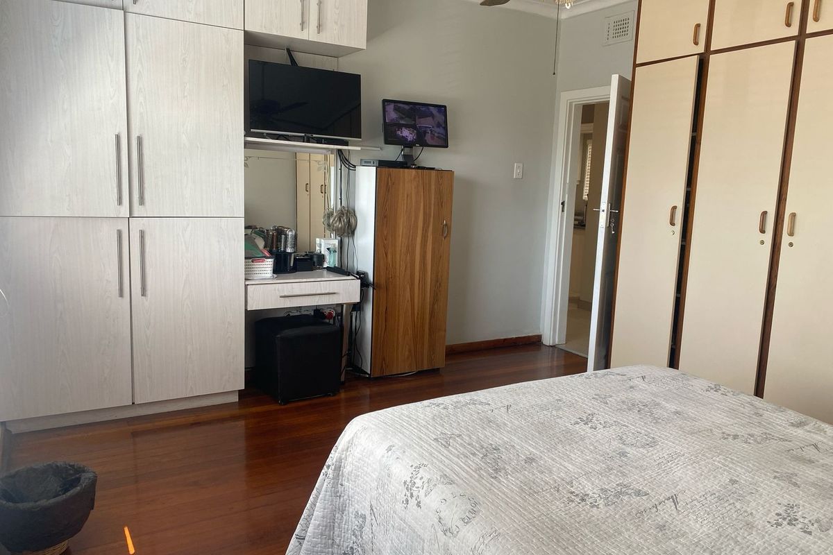 A bedroom featuring extensive built-in cabinetry, timber flooring, and a ceiling fan, providing ample storage space.