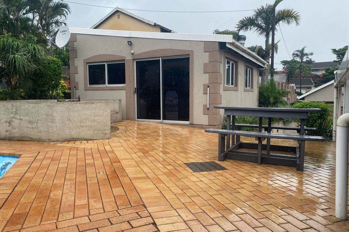 Exterior view of a detached outbuilding featuring a paved patio area, sliding glass doors, and adjacent swimming pool.
