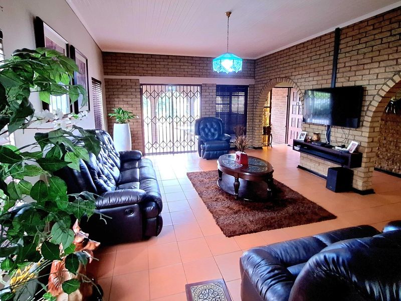 Spacious living room featuring exposed brick walls, tiled flooring, and a distinctive archway leading to adjacent areas, providing a warm and rustic atmosphere.