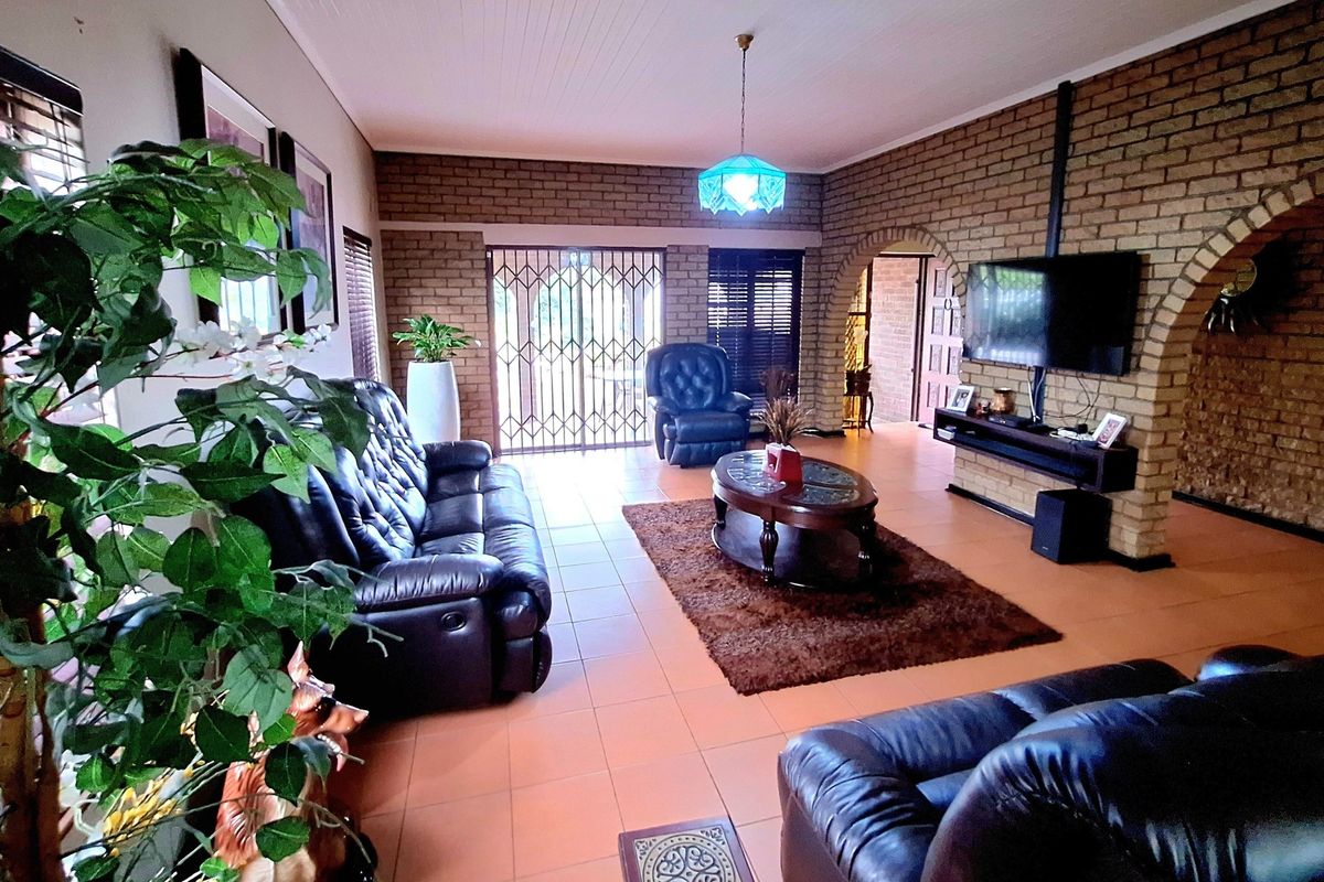 Spacious living room featuring exposed brick walls, tiled flooring, and a distinctive archway leading to adjacent areas, providing a warm and rustic atmosphere.