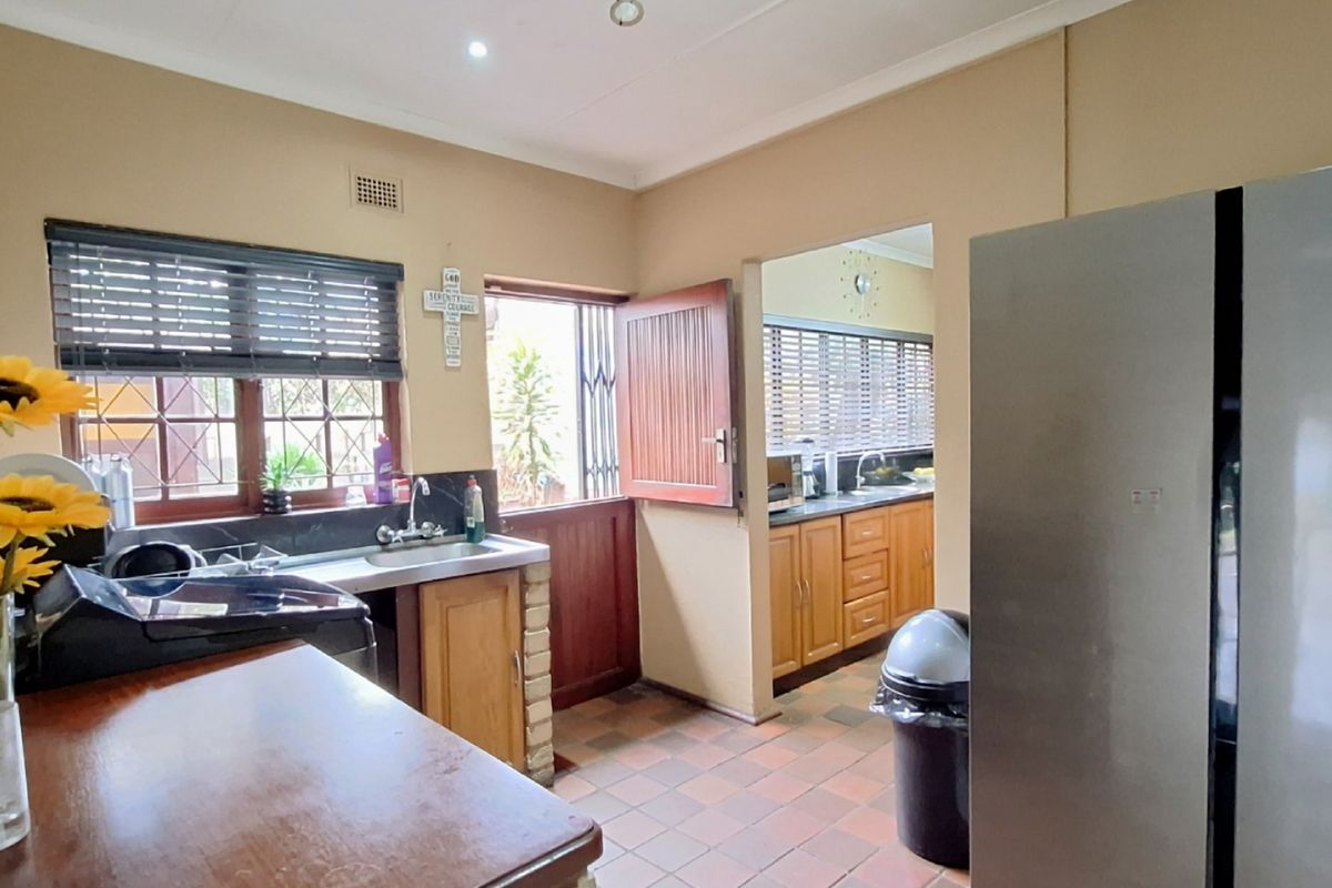 Functional kitchen featuring built-in cabinetry, tiled flooring, and direct access to the exterior through a secure timber door.