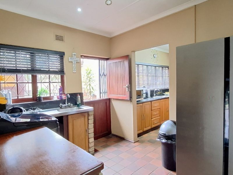 Functional kitchen featuring built-in cabinetry, tiled flooring, and direct access to the exterior through a secure timber door.
