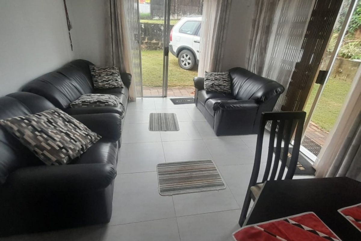 A bright living room featuring large sliding glass doors that provide direct access to the garden area and ample natural light.