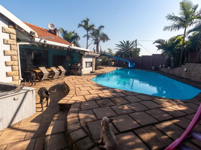 Outdoor entertainment area featuring a swimming pool with a slide, paved patio space, and stone-clad exterior wall details.