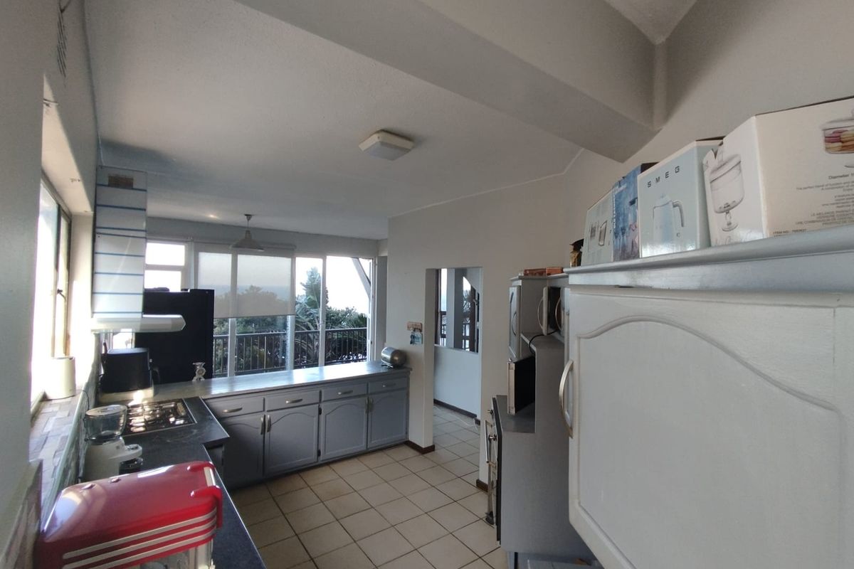 A functional kitchen featuring built-in cabinetry, a gas hob, and tiled flooring, with direct access to an outdoor balcony area.