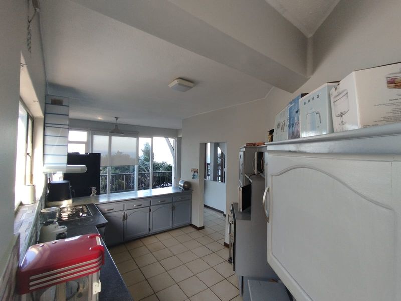 A functional kitchen featuring built-in cabinetry, a gas hob, and tiled flooring, with direct access to an outdoor balcony area.