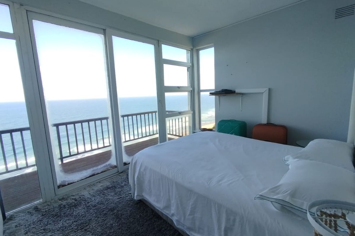 A bedroom featuring large sliding glass doors that open onto a balcony with direct ocean views.