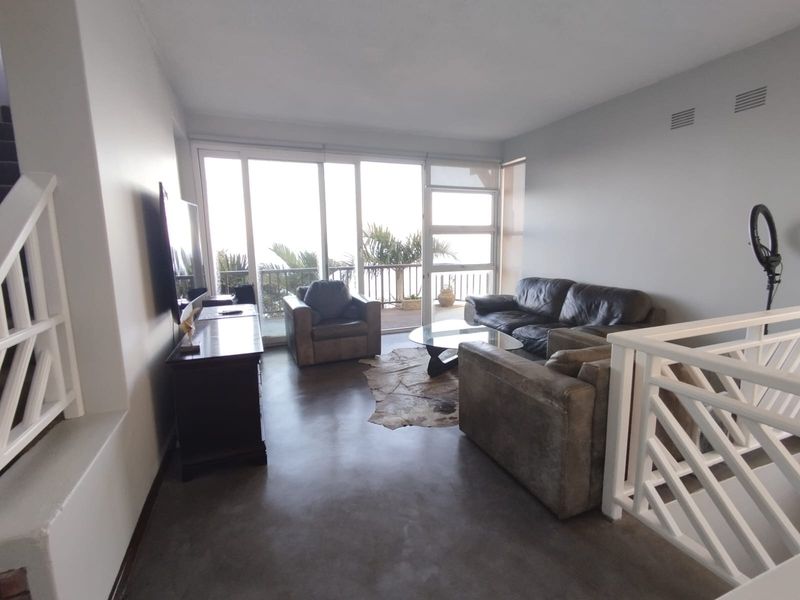 Spacious living room featuring polished concrete floors and large sliding glass doors that provide ample natural light and access to the outdoor area.