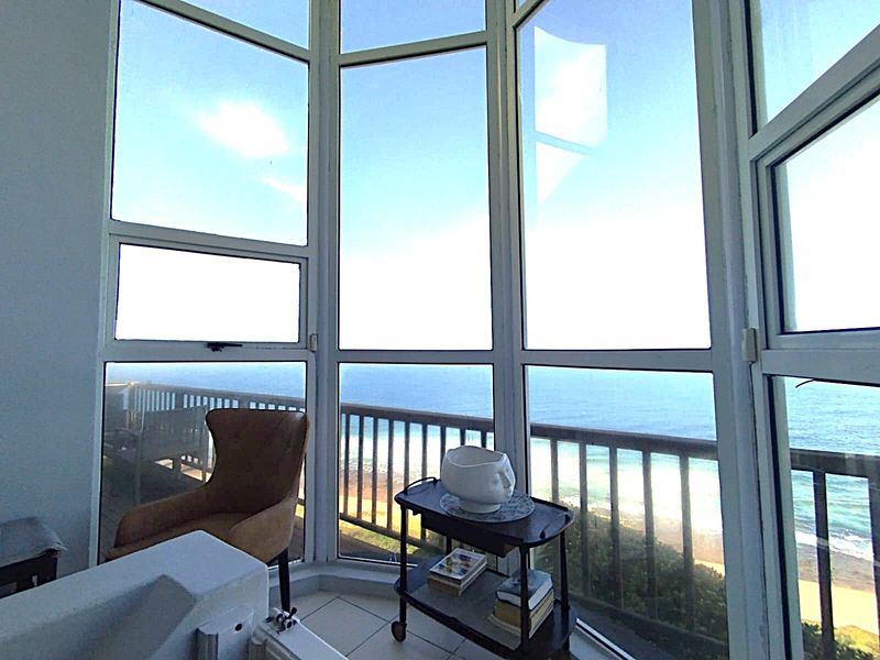 A bright living space featuring expansive bay windows that offer panoramic ocean views and natural light.