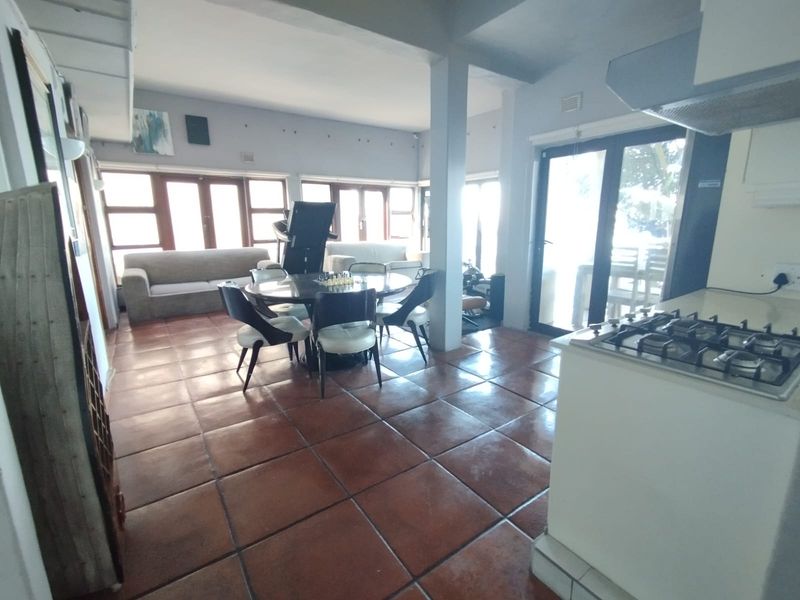 Open-plan living and dining area featuring terracotta floor tiles, a built-in gas hob, and large sliding doors providing access to the exterior.
