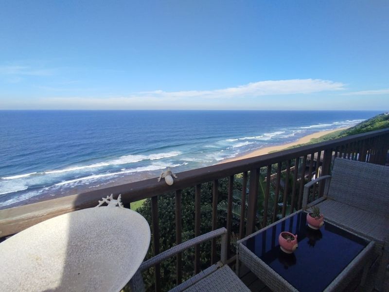 An elevated balcony featuring a timber balustrade and expansive, unobstructed views of the coastline and ocean.