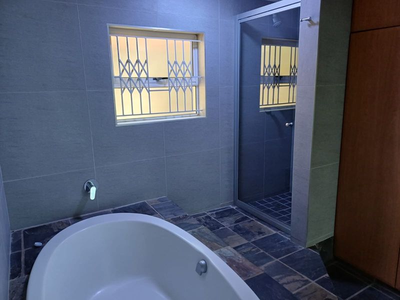 Modern bathroom featuring a freestanding bathtub, a separate walk-in shower with glass enclosure, and neutral wall tiling.