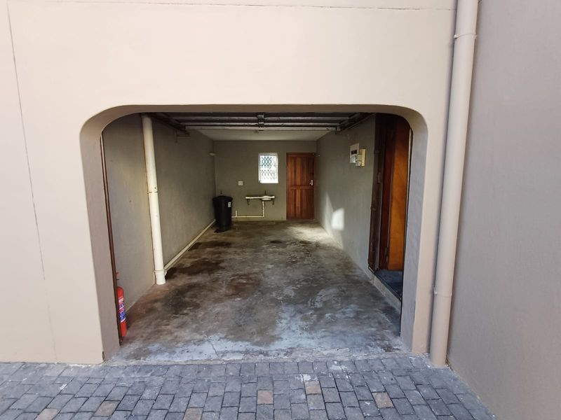 A functional garage space featuring a concrete floor, a wall-mounted basin, and direct access to the interior of the townhouse.