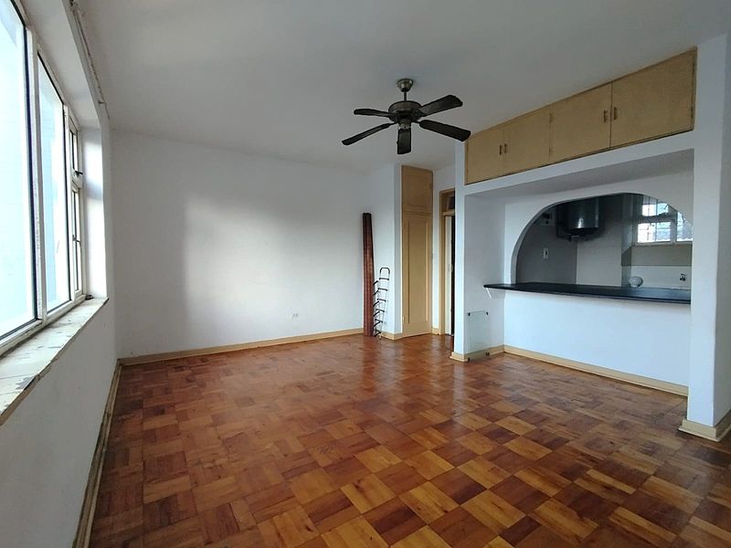 Open plan living area featuring classic parquet flooring, a ceiling fan, and a breakfast bar connecting to the kitchen space.