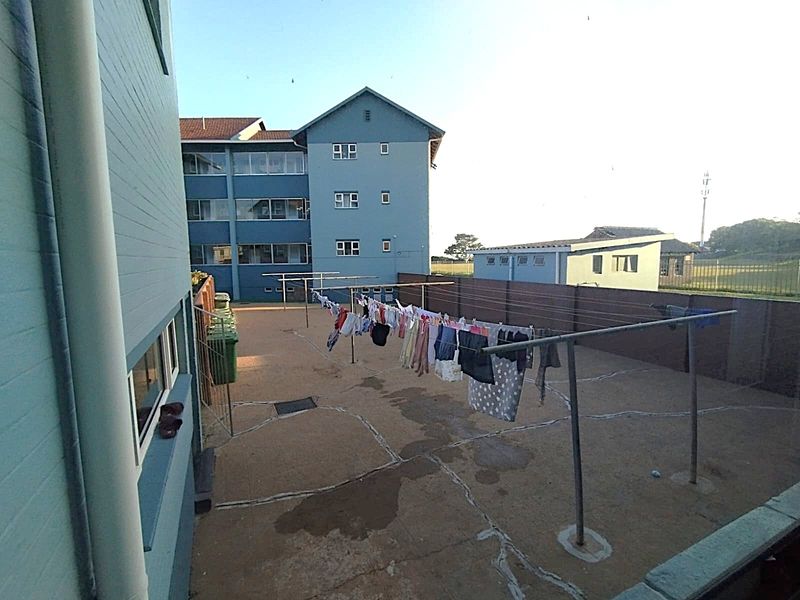 A communal paved rear courtyard area featuring metal washing lines and perimeter walling, serving the apartment complex.