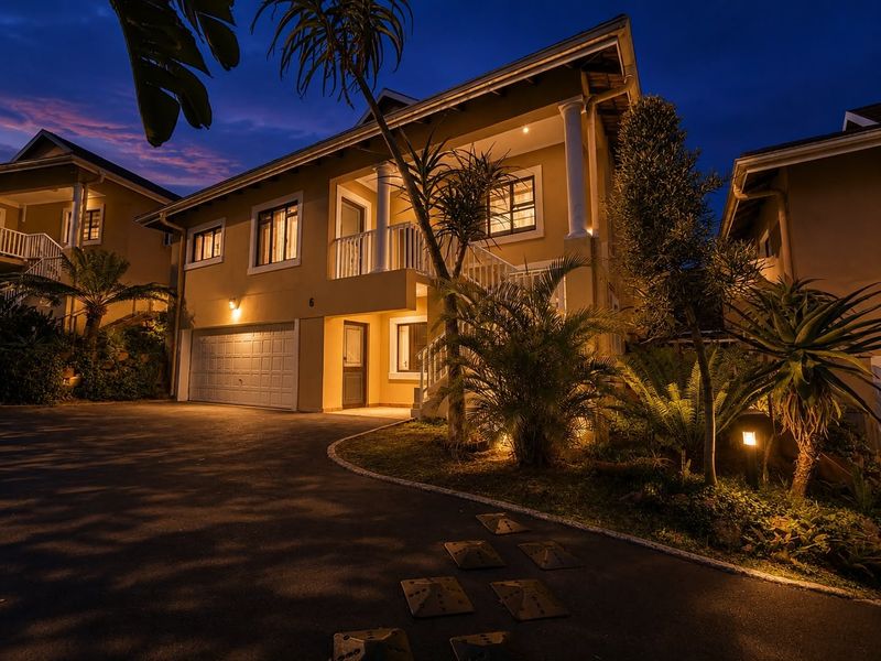 A well-maintained double-story residential property at dusk, featuring a paved driveway, integrated garage, and an inviting covered balcony entrance.
