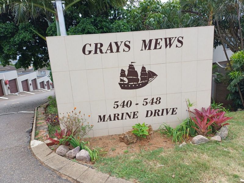 Entrance signage for Grays Mews townhouse complex located at 540-548 Marine Drive, featuring a paved driveway and landscaped garden area.