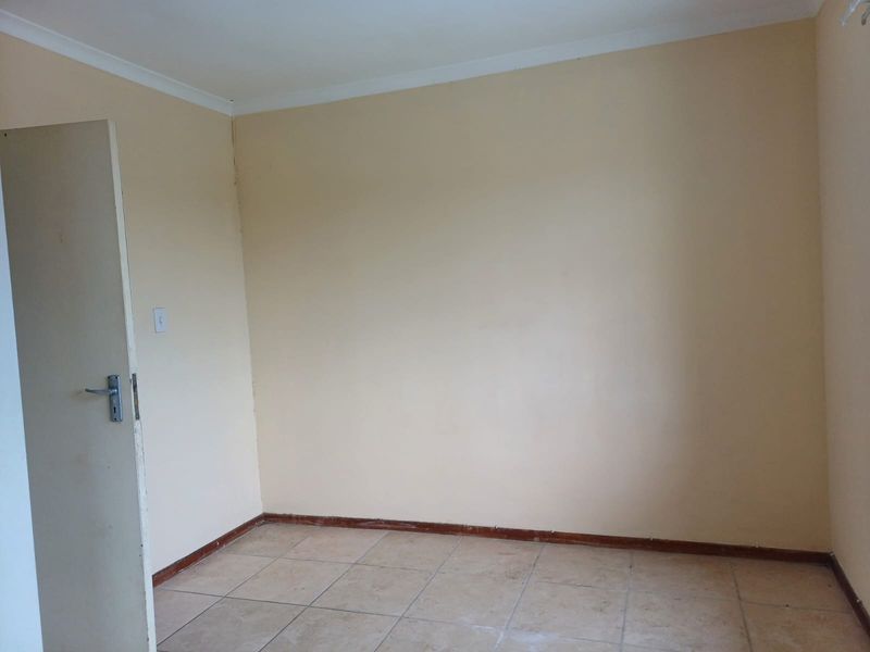 An empty bedroom featuring tiled flooring, coving, and a standard internal door, presenting a blank canvas for potential renovation or interior design updates.