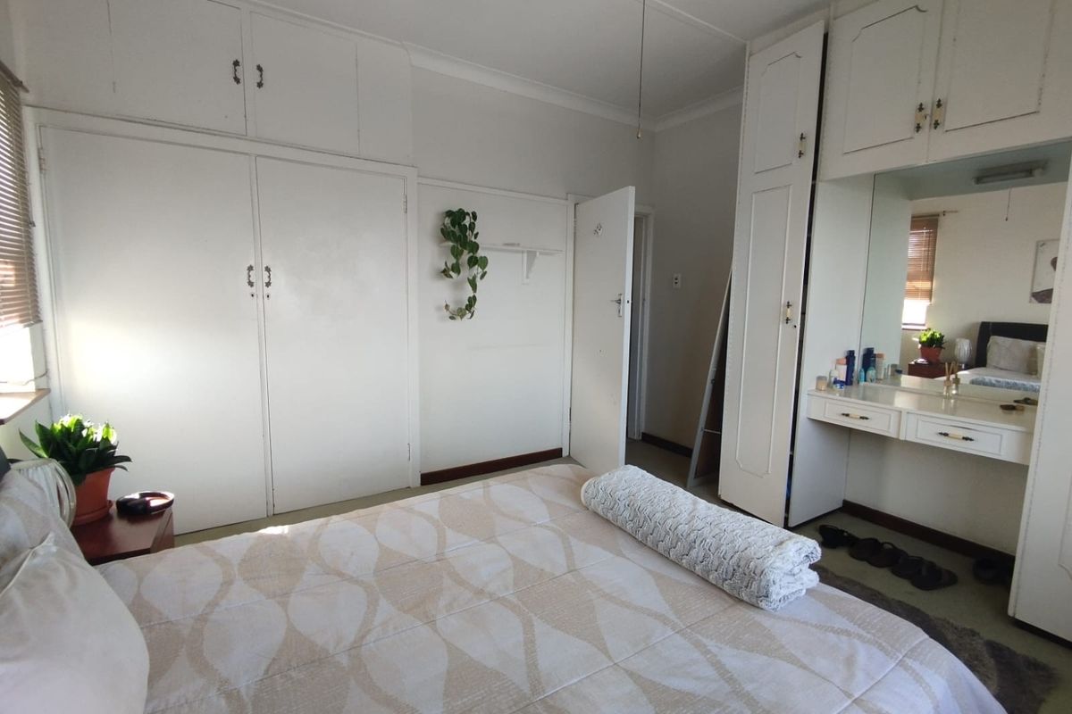 A bedroom featuring extensive built-in white cabinetry, integrated vanity with mirror, and a ceiling fan, offering ample storage space.