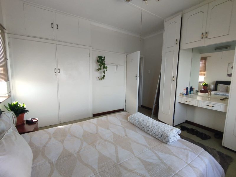 A bedroom featuring extensive built-in white cabinetry, integrated vanity with mirror, and a ceiling fan, offering ample storage space.