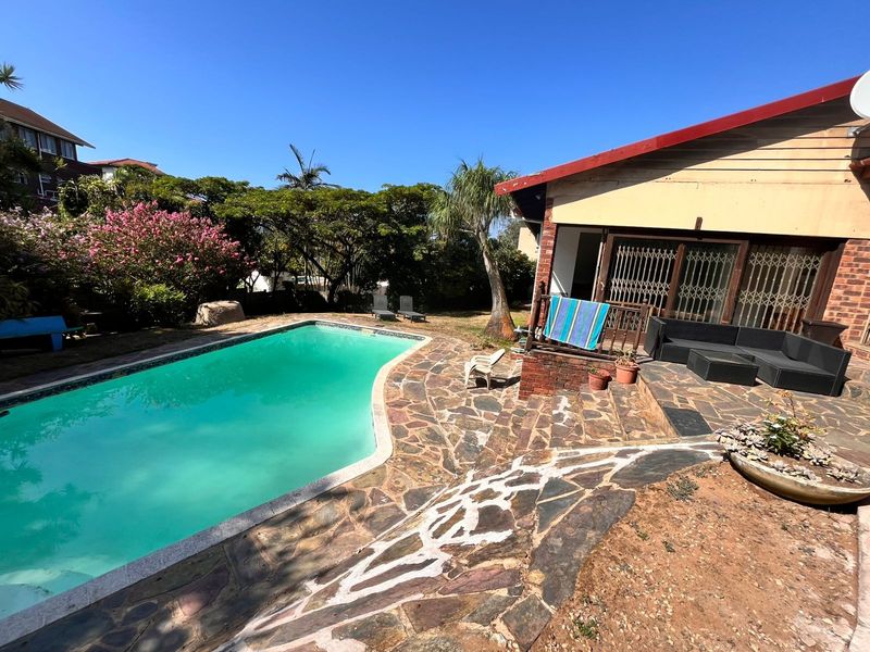 Outdoor pool area featuring a stone-paved patio, swimming pool, and direct access to the home via a security gate.