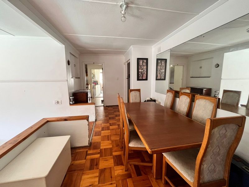 Dining area featuring traditional parquet flooring and a large wall-mounted mirror, providing a functional space with direct access to the kitchen area.