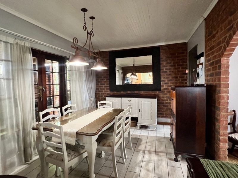 A dining room featuring exposed brick walls, tiled flooring, beadboard ceiling, and french doors providing natural light.