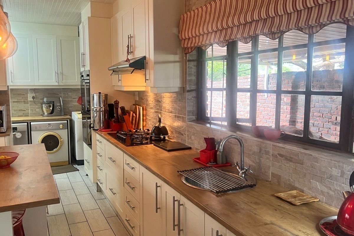 A well-maintained kitchen featuring white cabinetry, wooden countertops, a gas hob, built-in oven, and a tiled backsplash with a view to the exterior.