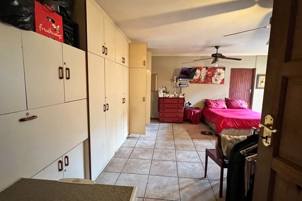 Spacious bedroom featuring extensive built-in cupboard storage, tiled flooring, and a ceiling fan.