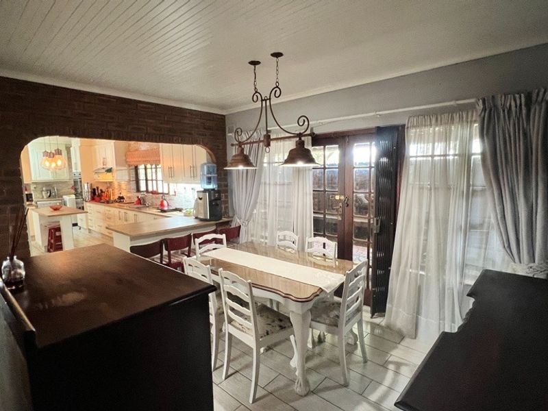 Open-plan dining area featuring exposed brickwork, tiled floors, and direct access to the outdoors, seamlessly connected to a functional kitchen space.