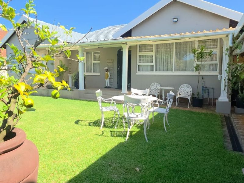 A well-maintained rear exterior view featuring a covered patio area, tiled roof, and a neat garden lawn.