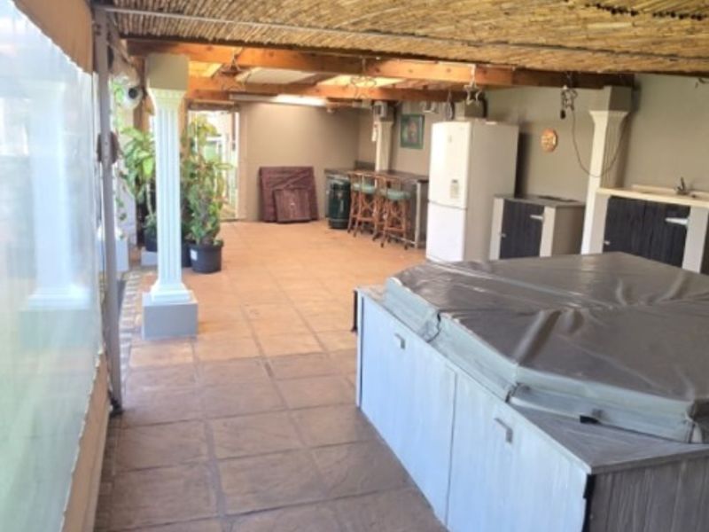 Covered outdoor patio area featuring a bamboo ceiling, tiled flooring, built-in bar cabinetry, and an integrated spa pool.