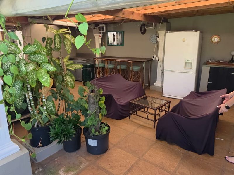 A covered outdoor patio area featuring tiled flooring, a timber pergola structure, and a built-in bar counter, ideal for outdoor entertaining.