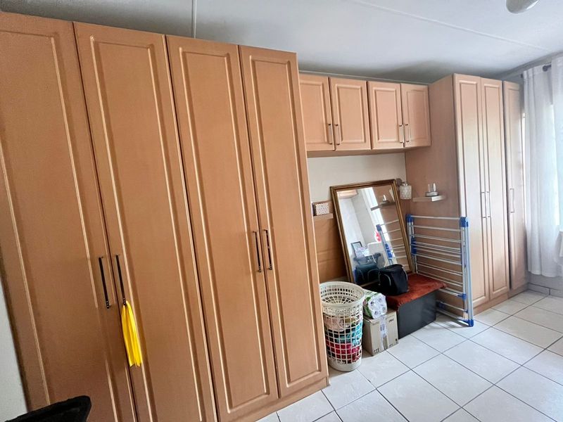 Bedroom featuring extensive built-in wooden cupboards and neutral tiled flooring, offering ample storage space.