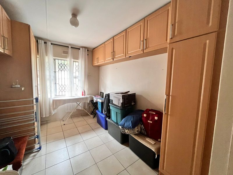 A functional laundry room featuring extensive built-in cabinetry, overhead storage cupboards, and durable tiled flooring, providing ample space for utility and storage needs.