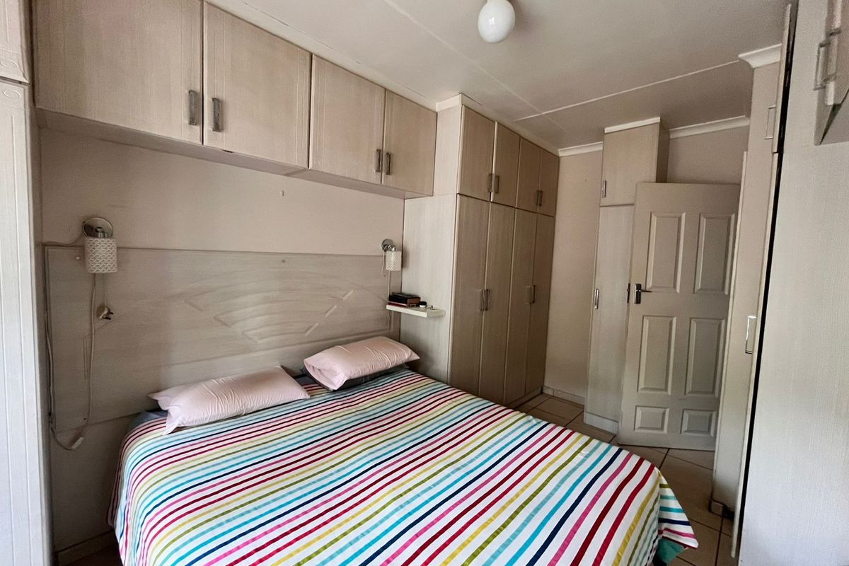 A functional bedroom featuring extensive built-in cabinetry, overhead storage units, and tiled flooring, providing ample storage space.