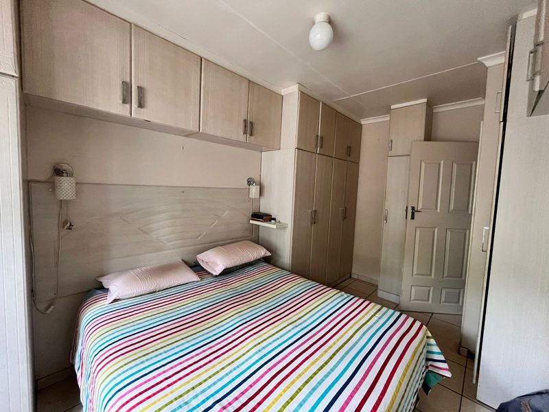 A functional bedroom featuring extensive built-in cabinetry, overhead storage units, and tiled flooring, providing ample storage space.